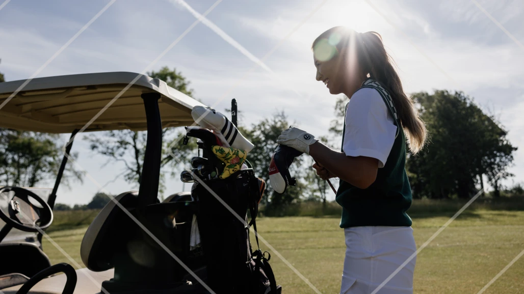 Mia Baker selecting a golf club from the back of a golf buggy during her collaboration with Ben Lomond Gin.