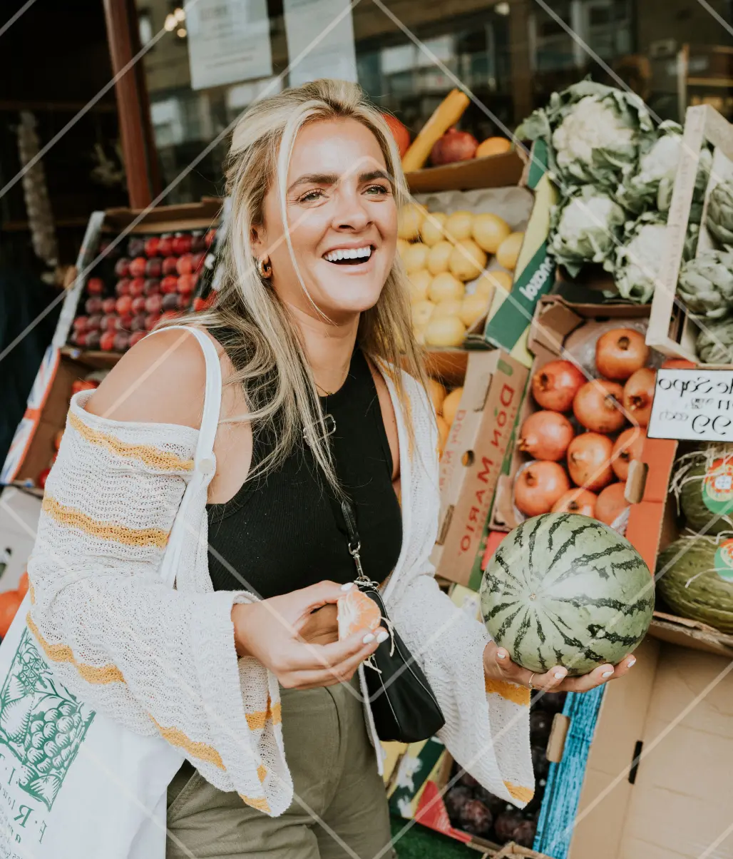 Just Jess Food smiling outside a fruit shop, holding a melon, sharing fresh produce pairings in collaboration with Ben Lomond Gin