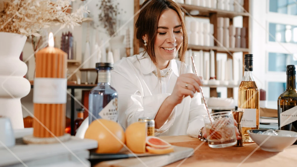 Alba, founder of Noord Candles, smiling while stirring ingredients in a glass to make her 'NO-ORDinary G&T' Ben Lomond Gin serve