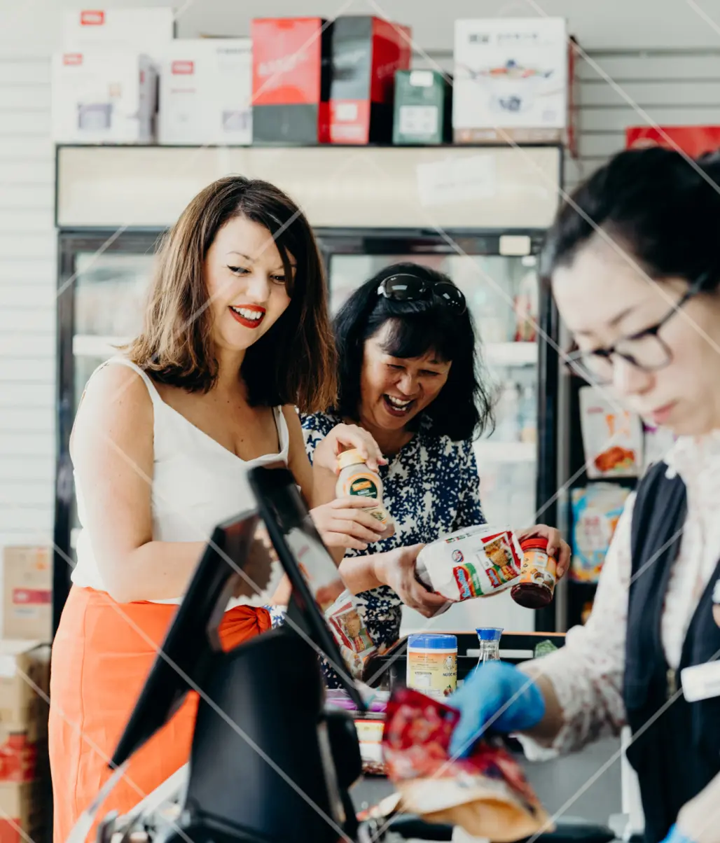 Julie Lin and her mum laughing while checking out at the shop after buying ingredients for Julie’s Ben Lomond Gin recipes.